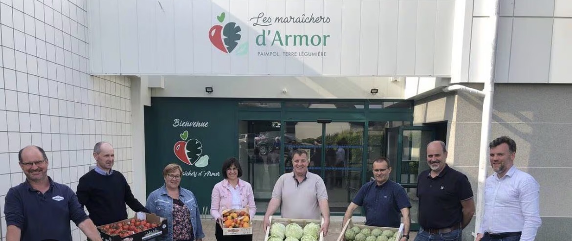 Équipe des Maraîchers d'Armor devant le site de Paimpol, avec des cageots de légumes